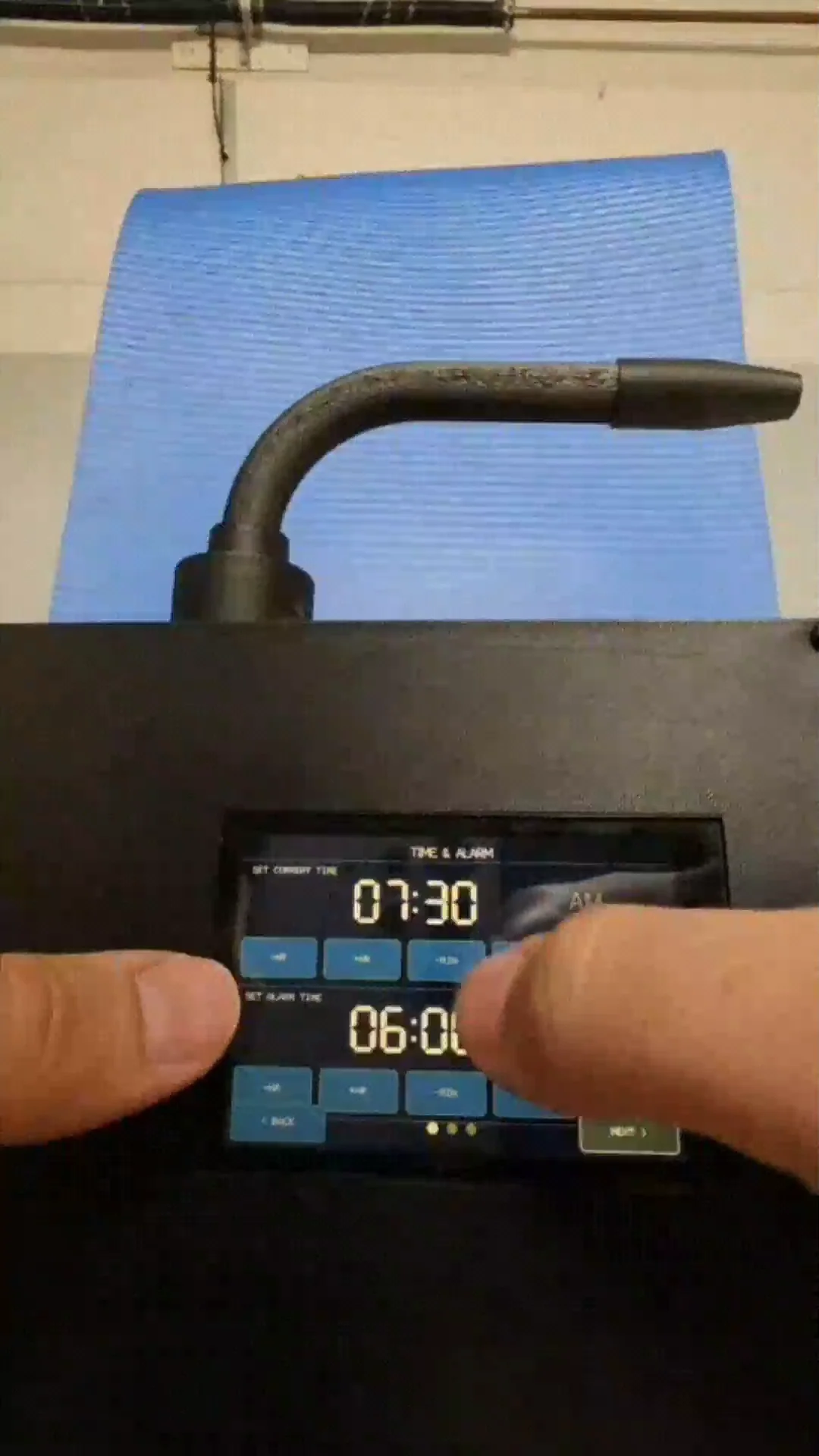 Working prototype: real photo of a hand operating the MistWake touchscreen, setting the alarm time